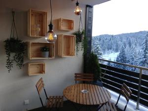 a table and chairs on a balcony with a view at DOR Apartment in Poiana Brasov