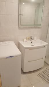 La salle de bains blanche est pourvue d'un lavabo et d'un miroir. dans l'établissement Apartamentai Renata, à Druskininkai