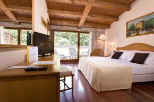 a hotel room with a bed and a desk with a computer at Poiano Garda Resort Hotel in Garda