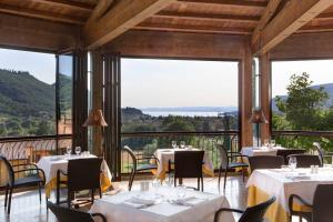 a restaurant with tables and chairs and large windows at Poiano Garda Resort Hotel in Garda