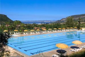 a large swimming pool with chairs and umbrellas at Poiano Garda Resort Hotel in Garda
