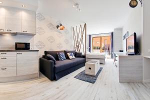 a living room with a couch and a kitchen at Apartamenty Sun & Snow Aura in Gdańsk