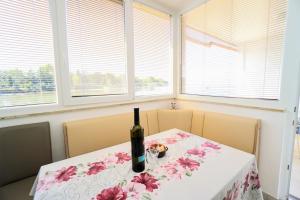 a bottle of wine sitting on a table in a room with windows at Apartment Mirela in Savudrija