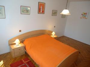a bedroom with a bed with orange sheets and two lamps at Apartment Gioia in Savudrija