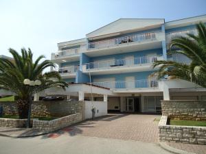 a blue building with palm trees in front of it at Luxury apartment Pelargonija in Monterosso Resort in Savudrija
