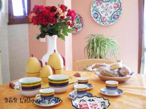 una mesa con un tazón de comida y un jarrón con flores en B&B L'alba Nel Golfo, en Castelsardo