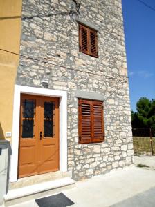 a stone building with a door and two windows at Apartments Ana in Savudrija