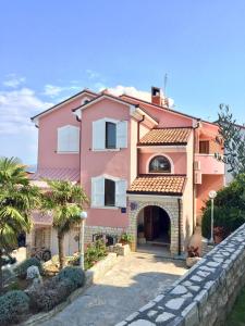 a pink house with a stone fence in front of it at Apartment Stefica in Crveni Vrh