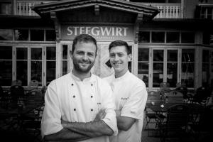 two chefs are standing in front of a restaurant at Welterbe-Wirtshaus Steegwirt in Bad Goisern