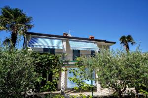 a house with blue and white windows and palm trees at Apartment Nino Savudrija in Bašanija