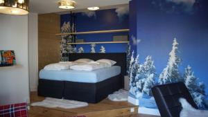 a bedroom with a bed with snow covered trees on the wall at ALPENLIEBE Design Hotel in Inzell
