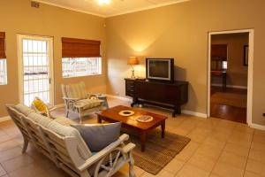 uma sala de estar com um sofá e uma televisão em Hazenjacht Karoo Lifestyle - Oom Manus se Huis em Oudtshoorn