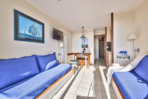 a living room with a blue couch and a table at Appartement l'Archipel - Vue mer exceptionnelle et bassins aquatiques du 29 avril au 15 sept in Talmont