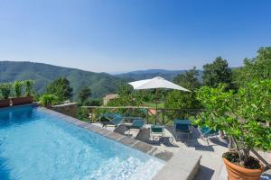 a swimming pool with chairs and an umbrella at Casa Margherita 3 by PosarelliVillas in Piegaio