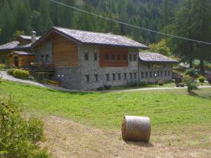 una casa grande en un campo con un fardo de heno en Hotel Les Granges en La Thuile