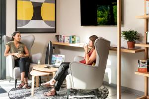 two women sitting in chairs in an office talking on the phone at Aparthotel Adagio access Colombes La Défense in Colombes +10 photos