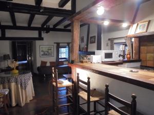 a kitchen with a bar with chairs and a microwave at Casa Rural La Central-Peñagorda in El Barco de Ávila