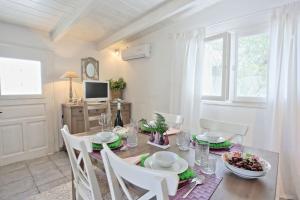 a dining room with a table and chairs and a television at Lili Luxury Cottage in Gaios