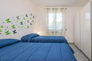 two beds in a bedroom with blue sheets and butterflies on the wall at Villa Francesco...graziosa, moderna, confortevole! in Lascari