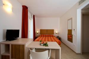 Club Village & Hotel Spiaggia Romea في ليدو دي فولانو: غرفة نوم بسرير وطاولة مع صحن من الفواكه