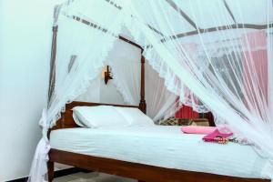 a bedroom with a canopy bed with white curtains at Raviru Guest Mirissa in Mirissa