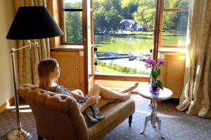 a woman sitting on a couch looking out of a window at Hotel Gut Klostermühle natur resort & medical spa in Alt Madlitz