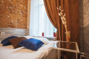 uma cama com almofadas azuis num quarto com uma janela em Avangard Hotel em São Petersburgo