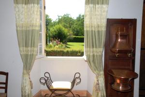 ein Stuhl vor einem Fenster mit Vorhängen in der Unterkunft Le Logis du Port in Domme