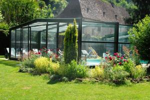 ein Glashaus in einem Garten mit Blumen in der Unterkunft Le Logis du Port in Domme