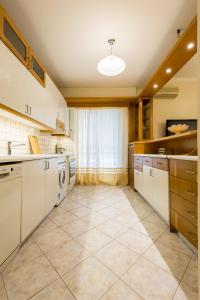 uma grande cozinha com armários brancos e piso em azulejo em Classy 2 bedroom apartment near Acropolis & Metro em Atenas