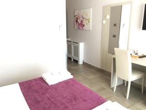 Habitación con mesa y alfombra púrpura en Alludo Aparthotel b&b en Agrigento