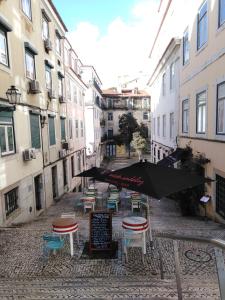 リスボンにあるAwarded 3 bedrooms upscale flat@Chiado Bairro Altoのテーブルと椅子と傘が並ぶ通り