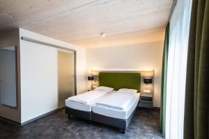 a bedroom with two beds and a green headboard at Hotel Holzscheiter in Lottstetten