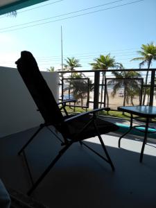een stoel op een balkon met uitzicht op het strand bij Santa Helena Pousada in Guarujá