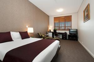 a hotel room with a large bed and a desk at Adabco Boutique Hotel Adelaide in Adelaide