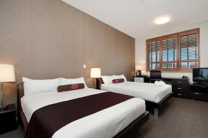 a hotel room with two beds and a television at Adabco Boutique Hotel Adelaide in Adelaide
