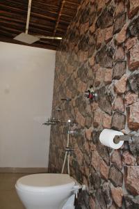 a bathroom with a stone wall and a toilet at Sea Shades Palolem Resort in Palolem