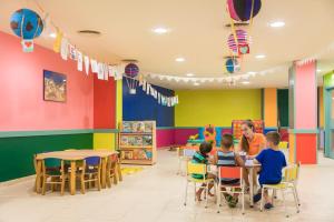 un jardin d'enfants avec des enfants assis à des tables dans une salle de classe colorée dans l'établissement htop Royal Star & SPA #htopFun, à Lloret de Mar