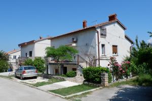 a white house with a car parked in front of it at Apartment Marija in Premantura