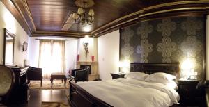 a bedroom with a large bed and a chandelier at Guesthouse Iridanos in Kalabaka