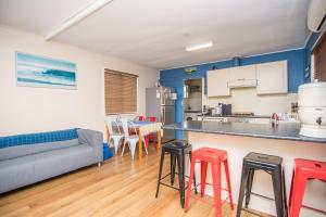 a kitchen and living room with a couch and stools at The Gee Beach House in Guilderton