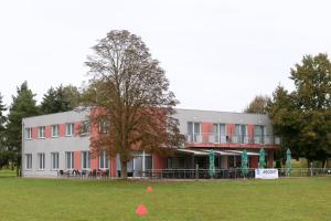 a building with a tree in the middle of a field at Penzion Letališče in Murska Sobota