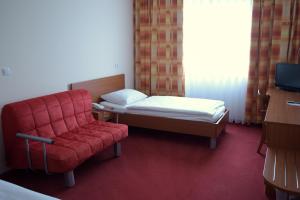 a bedroom with a bed and a red chair at Penzion Letališče in Murska Sobota
