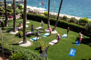 a group of people doing yoga on the grass near the ocean at Fame Residence Kemer & Spa in Kemer