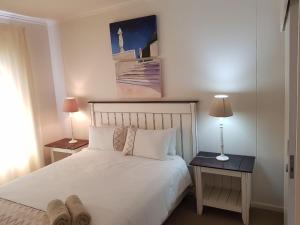 1 dormitorio con 1 cama blanca y 2 mesas con lámparas en Point Village Accommodation - Portobello 26 en Mossel Bay