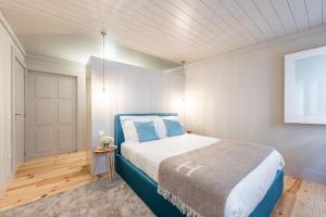 a bedroom with a blue bed and a white wall at Casa da Cera da Porta da Vila in Guimarães