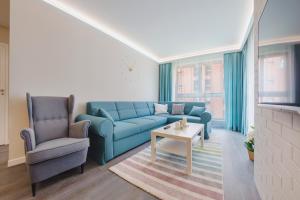 a living room with a blue couch and two chairs at Apartamenty Sun & Snow Aura in Gdańsk