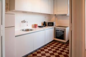 a small kitchen with white cabinets and a sink at METRO APARTMENT in Porto