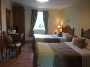 a hotel room with two beds and a desk at Ashleigh House Bed & Breakfast in Monaghan