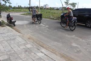 a man and a woman riding bikes on a road with a dog at Sun Paradise Villa Hoi An in Hoi An